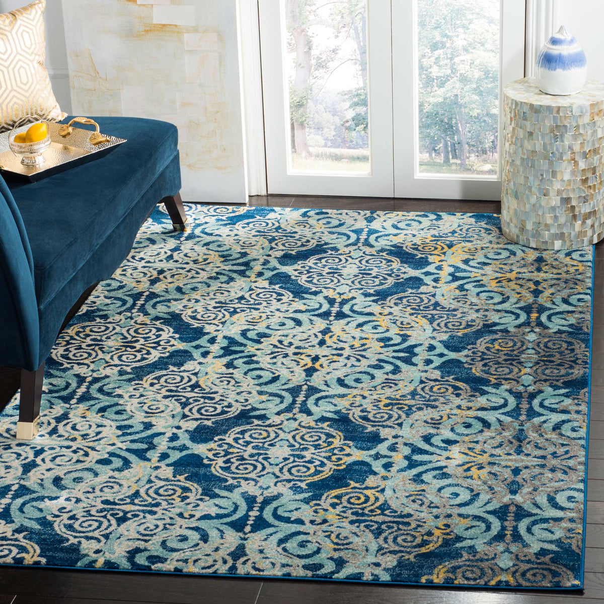 Swirling light blue and ivory medallions brighten the royal blue rug beneath a deep blue sofa.