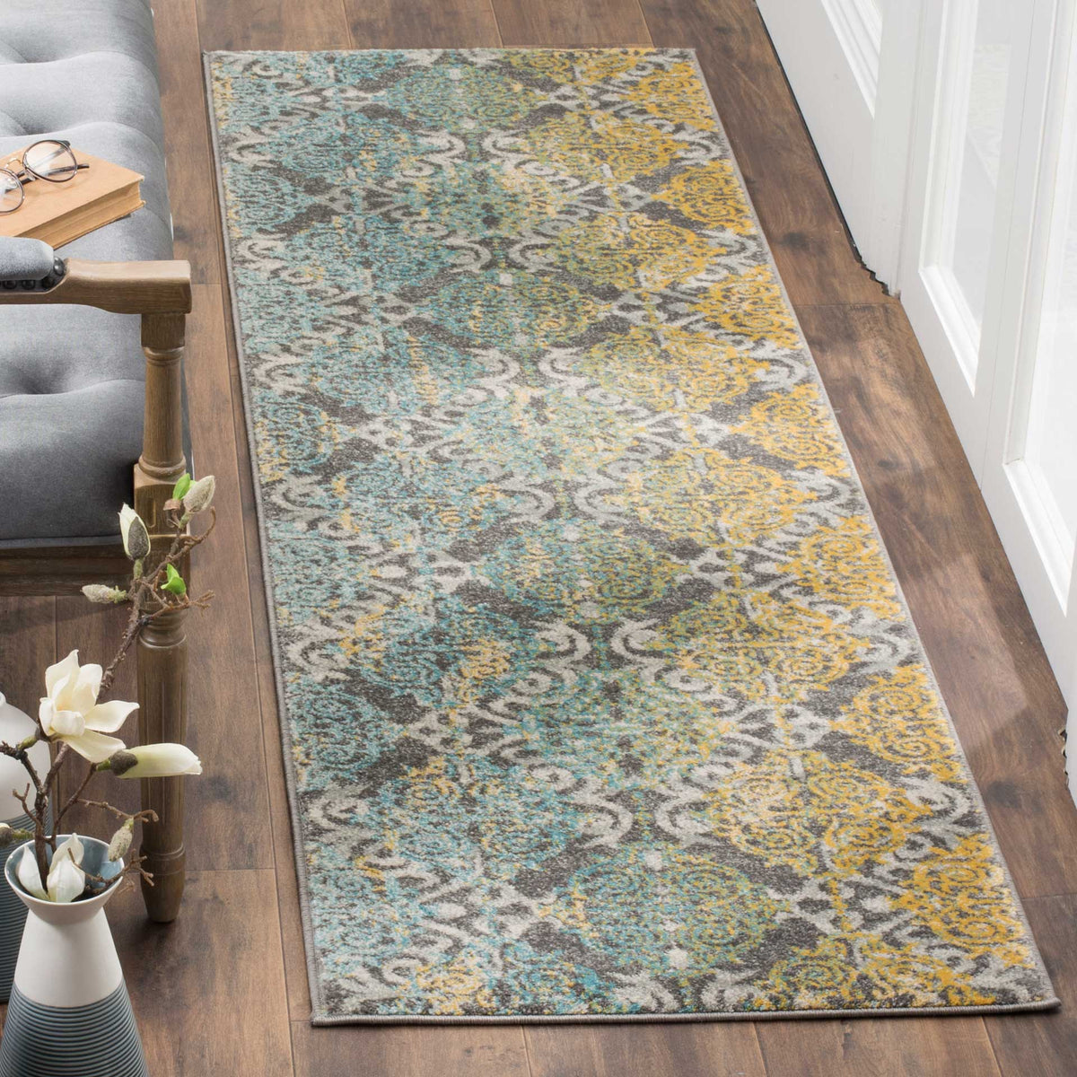 A narrow runner layers flowing gray scrollwork with aqua and golden yellow accents