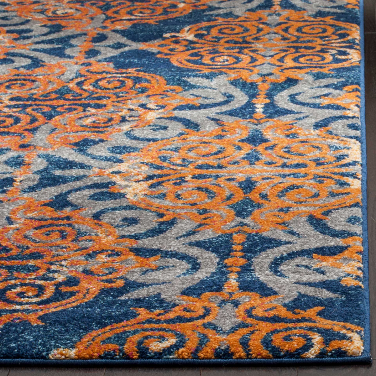 Orange scrollwork and textured blue pile meet neatly bound edges on this rug.