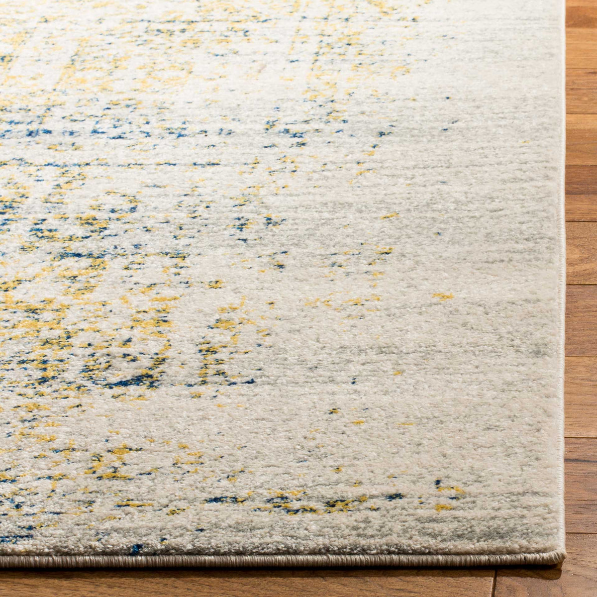 A bound rug edge frames the ivory pile, flecked with faded blue and golden pattern.