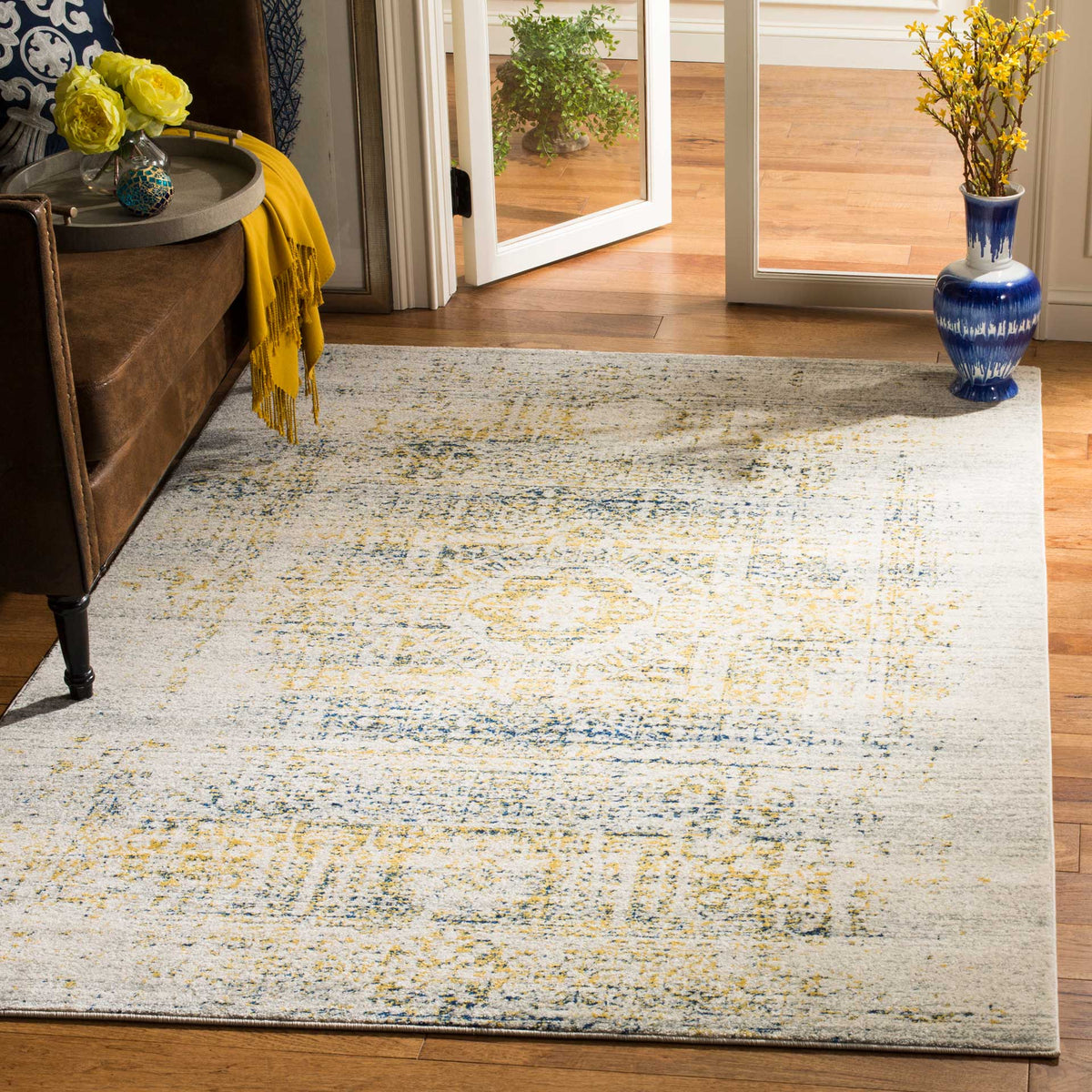 An ivory-and-blue medallion rug brings soft, weathered pattern beside a brown sofa.