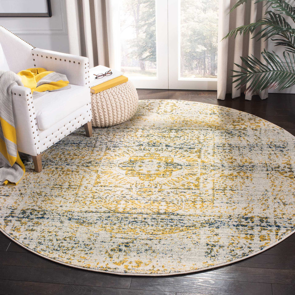Vintage-inspired motifs bring blue and gold warmth to a round ivory rug beneath a cozy chair.