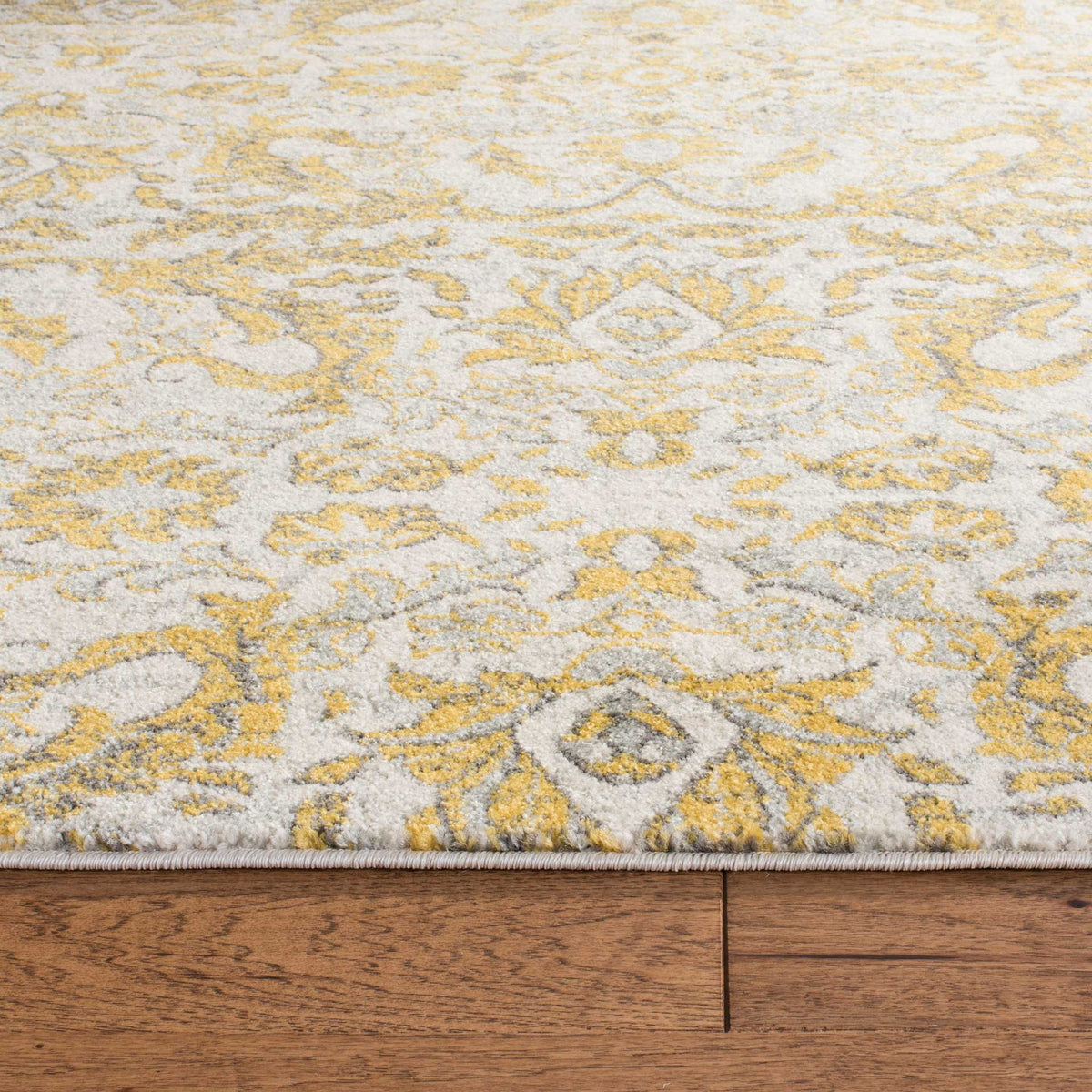 Textured ivory pile and a neatly bound edge bring definition to golden floral scrollwork