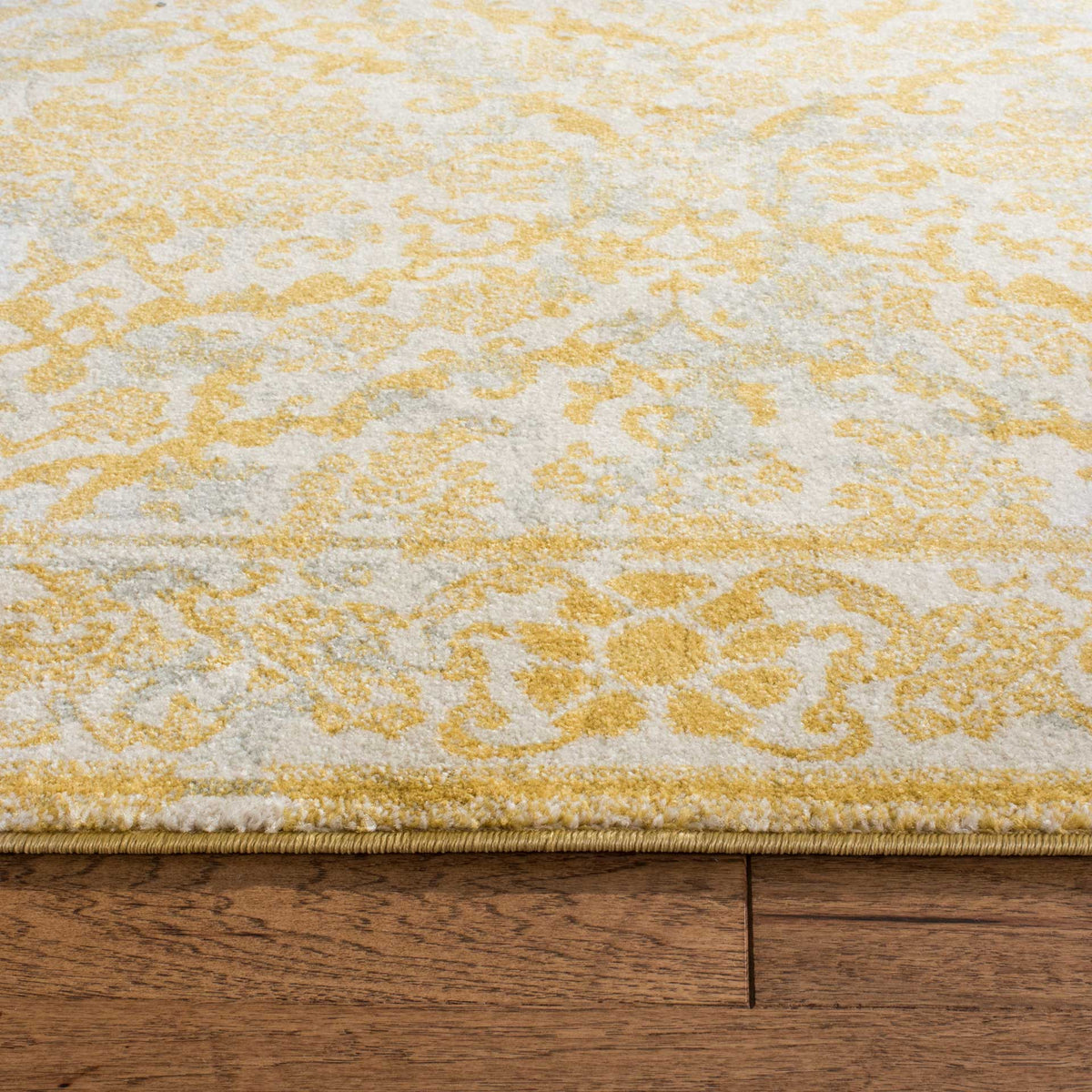 Softly textured ivory and gold scrollwork meets a neatly finished rug edge