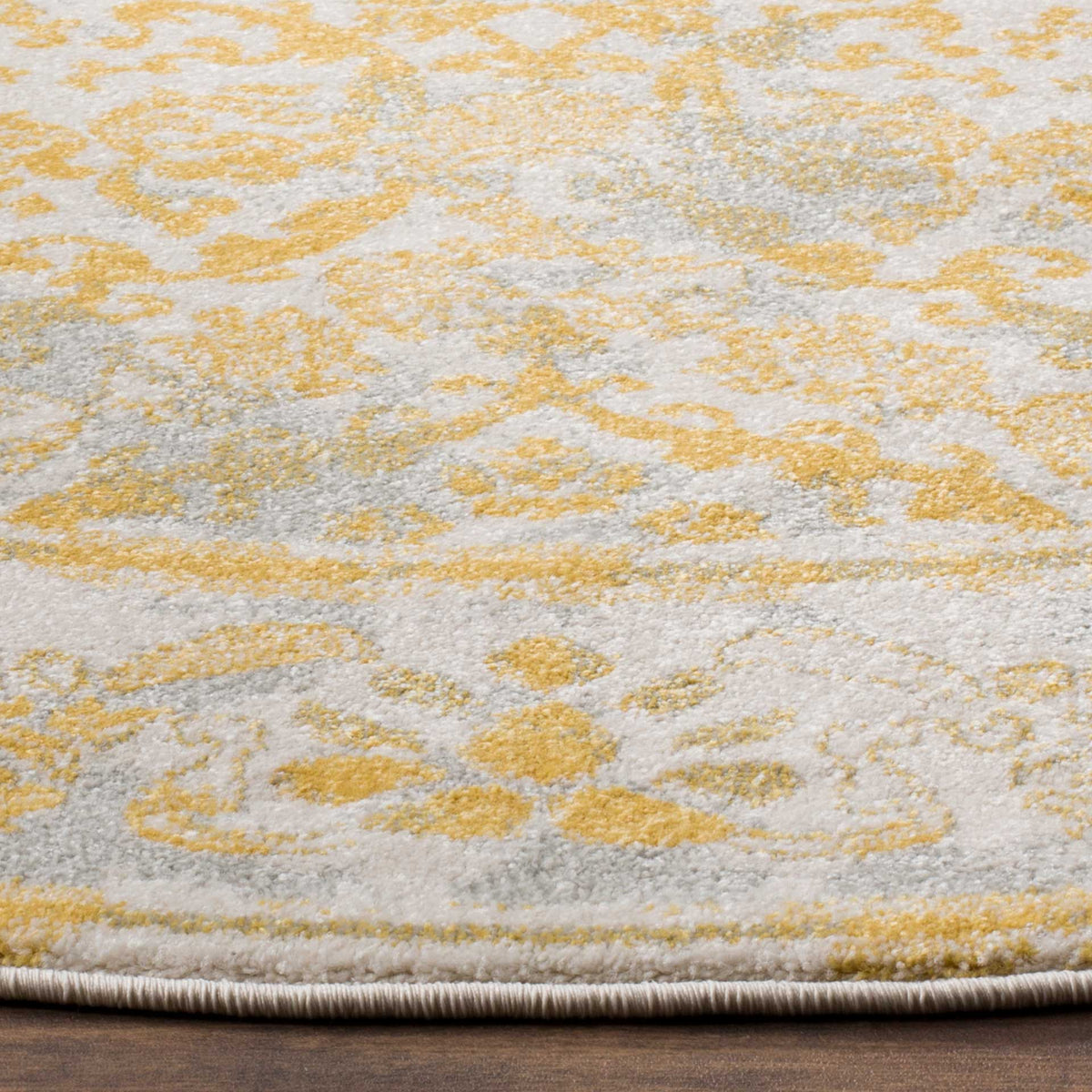 Gold and gray floral motifs enrich the ivory pile, finished with a neatly bound edge.