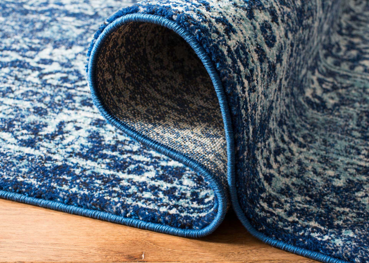 A turned rug edge reveals sturdy woven backing beneath the navy and ivory pile