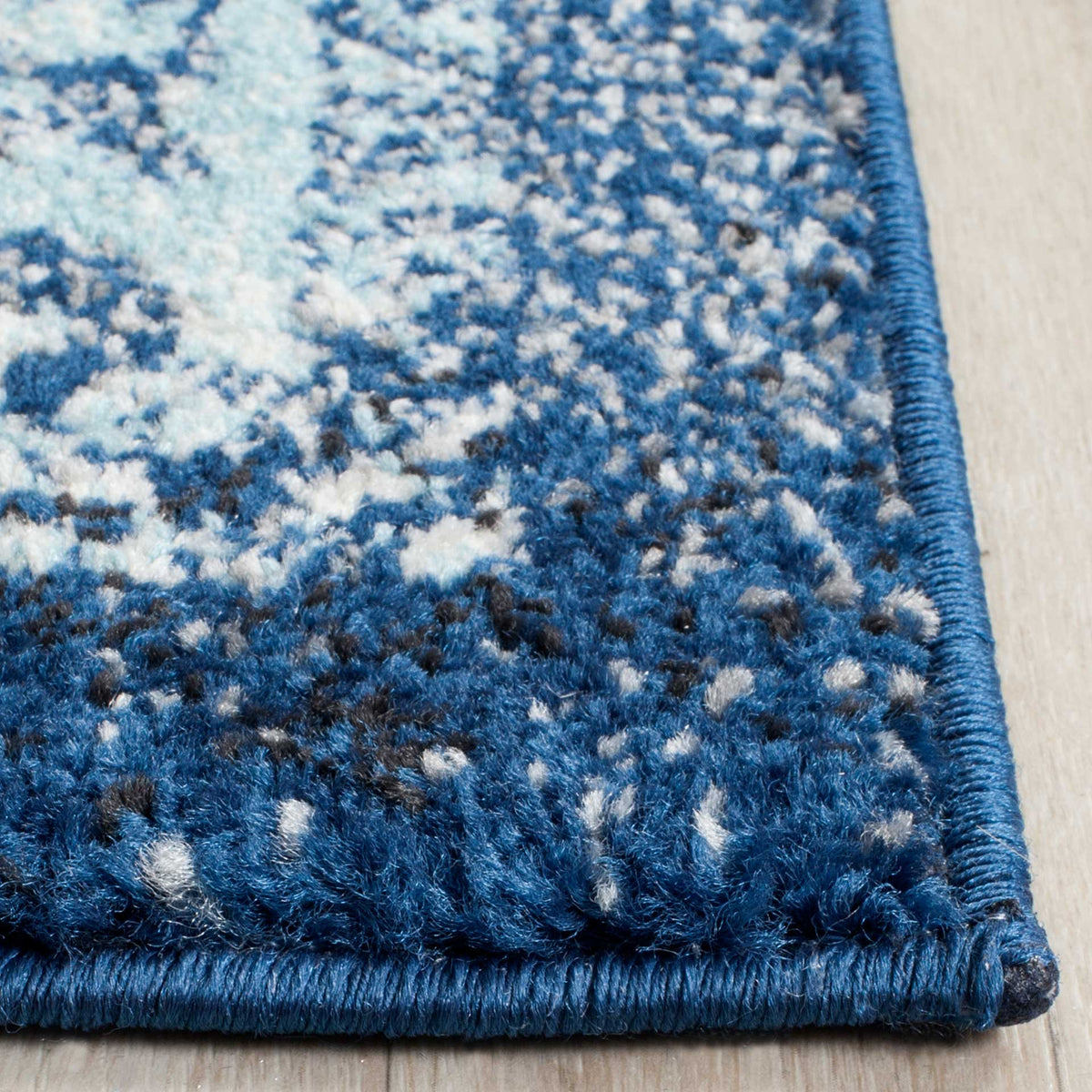 Dense navy and ivory patterned pile is finished with a dark blue bound edge