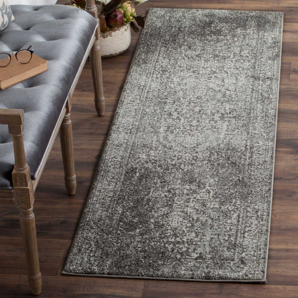 Gray and ivory runner brings a richly distressed design to wood flooring beside a tufted bench