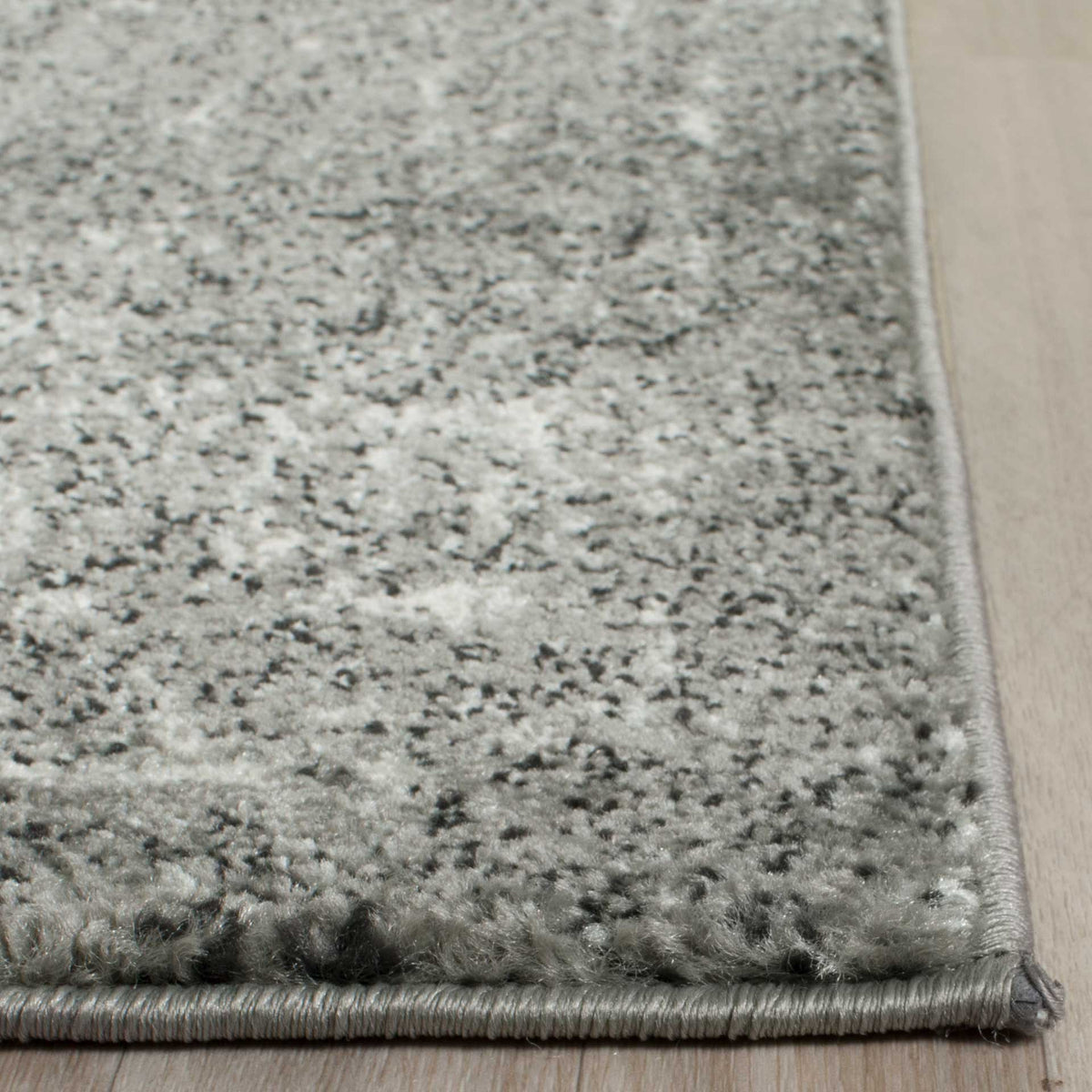 Mottled gray and ivory pile meets a neatly finished woven edge