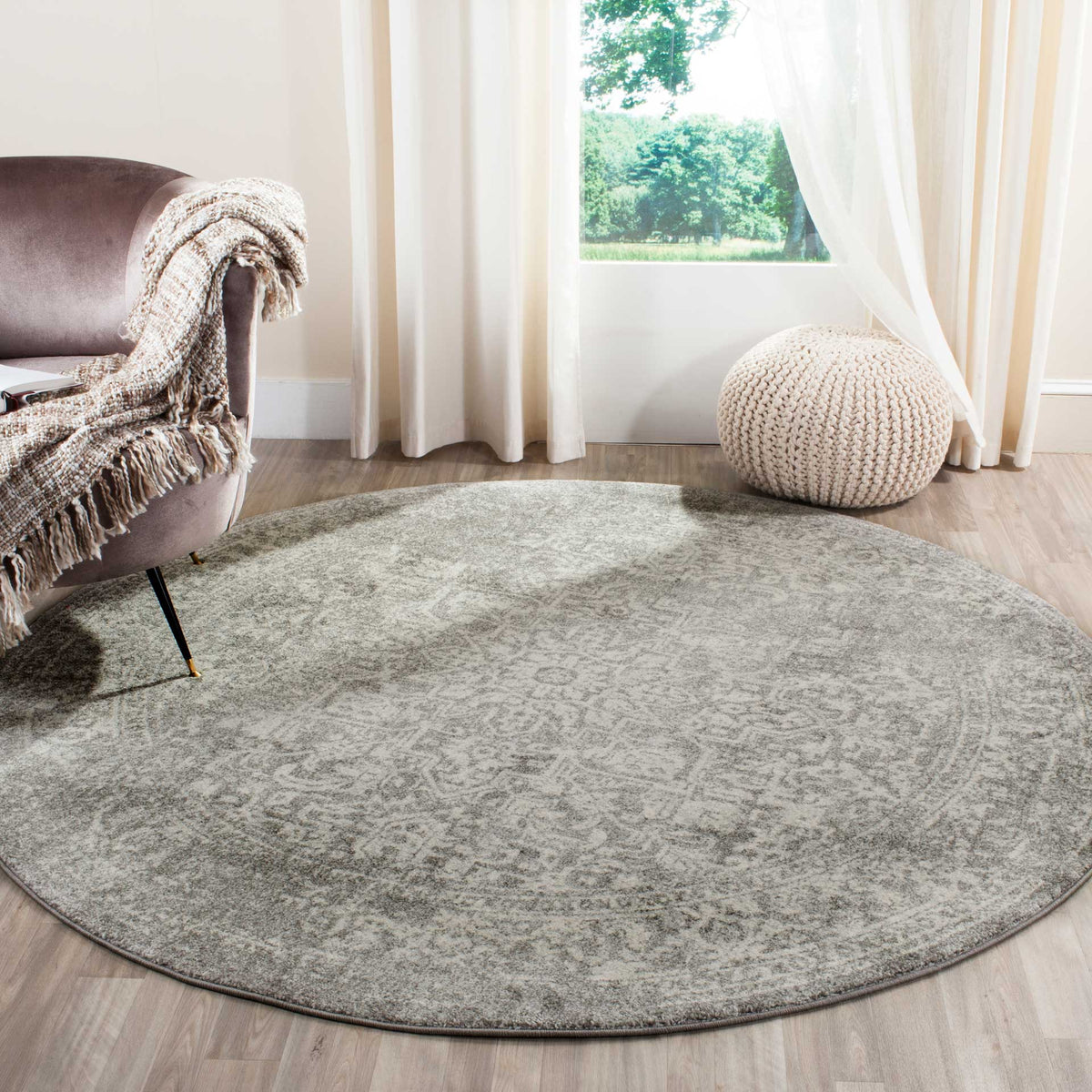 A silver and ivory round rug lends subtle, weathered pattern to a bright sitting area.