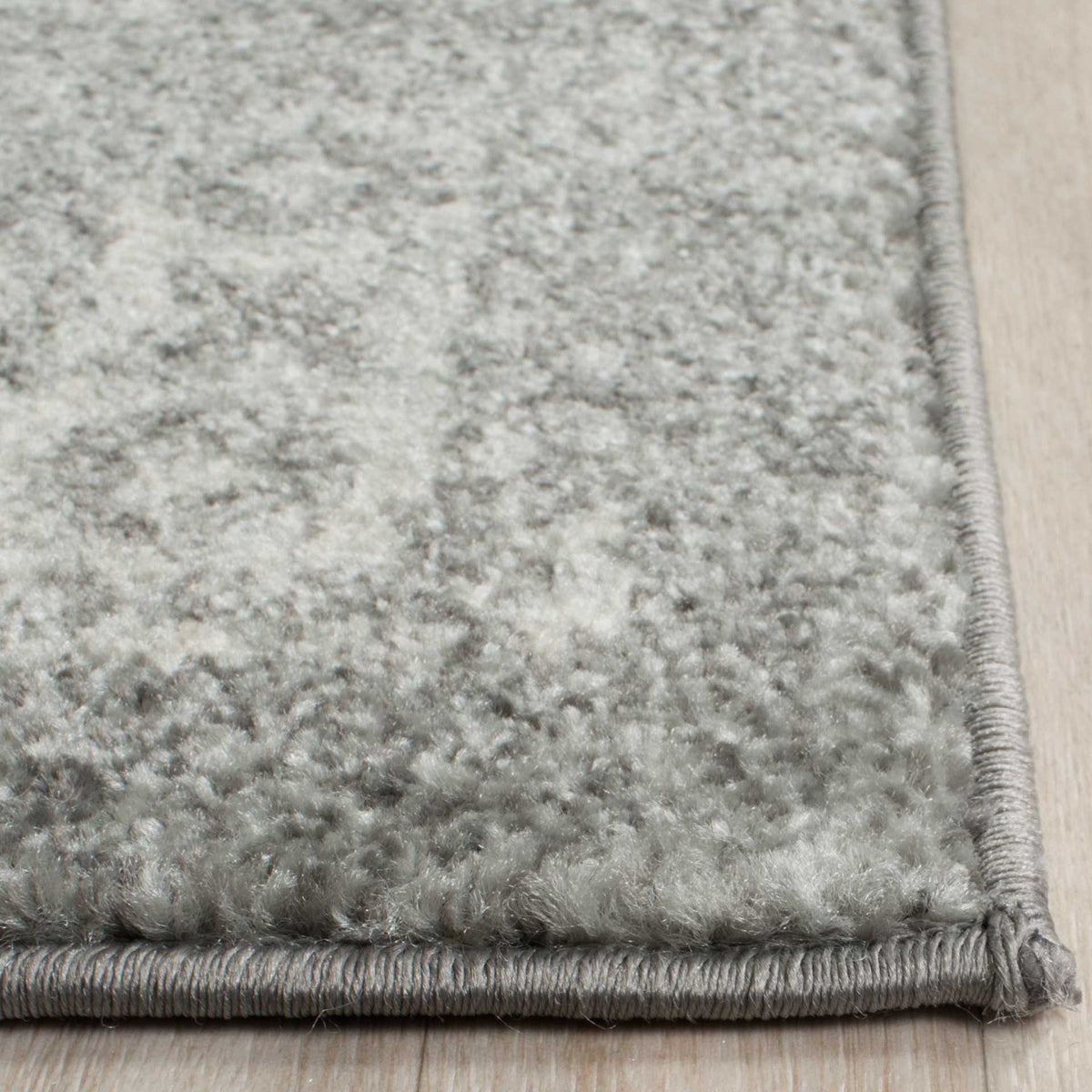 Soft silver and ivory pile meets a neatly bound gray edge