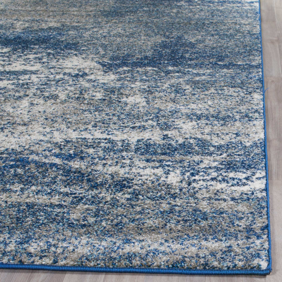 Speckled blue and ivory fibers pair with slim blue binding along the rug's edge.