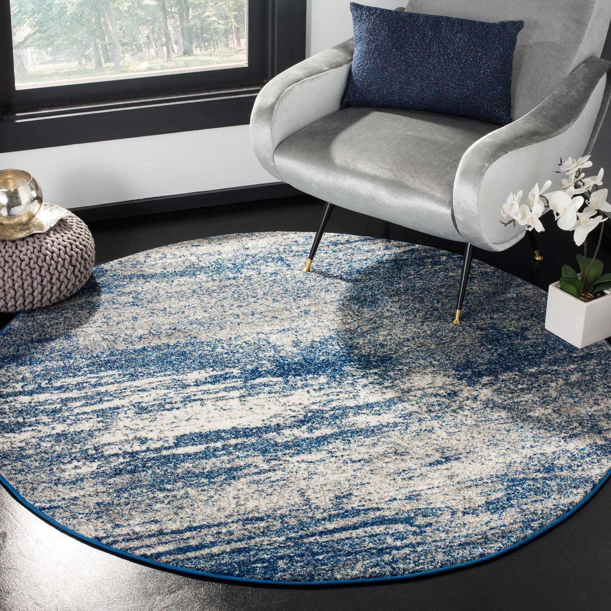 A round navy and ivory rug adds an artistic foundation beneath a cozy lounge chair.
