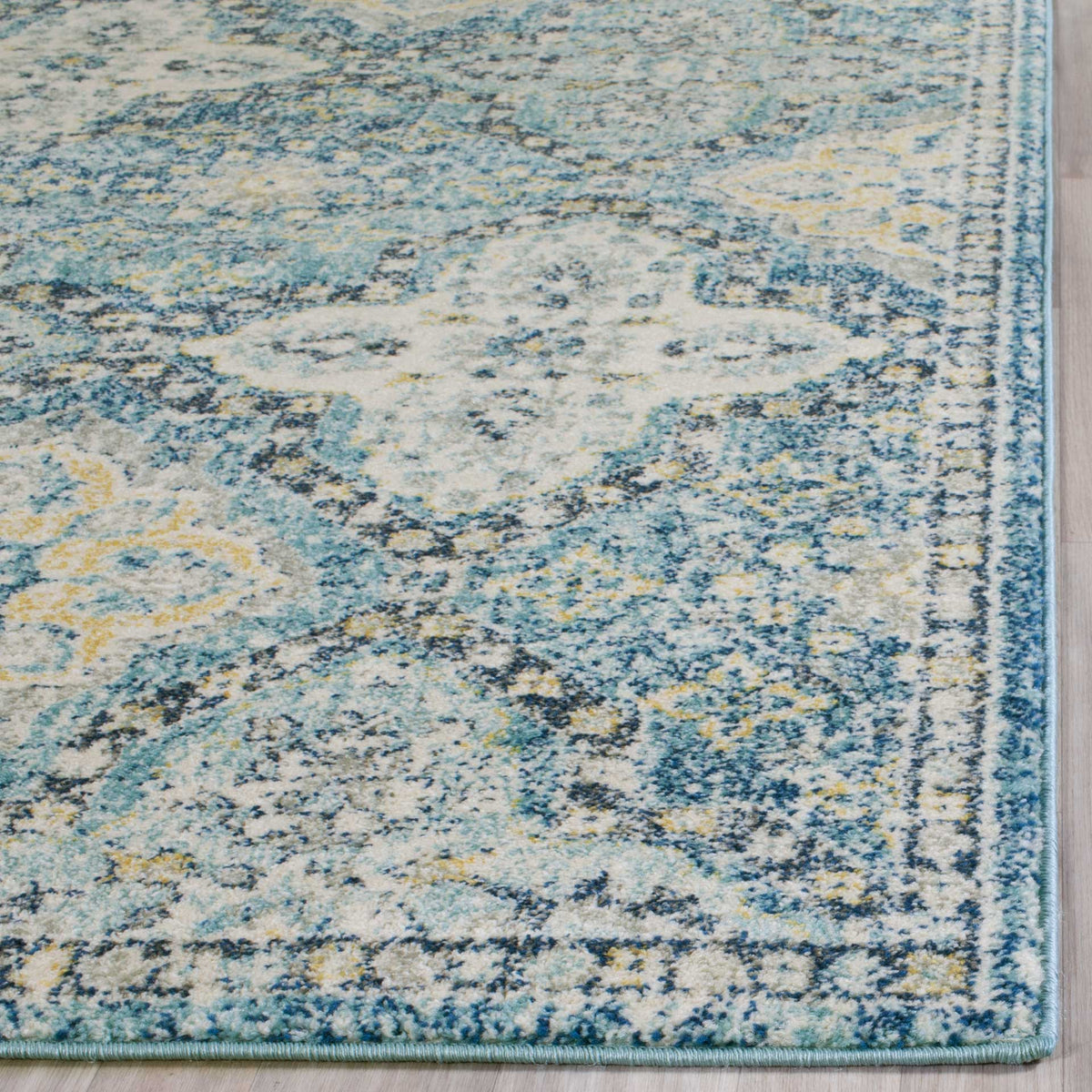 A neatly bound edge frames the rug's mottled blue and ivory floral pattern