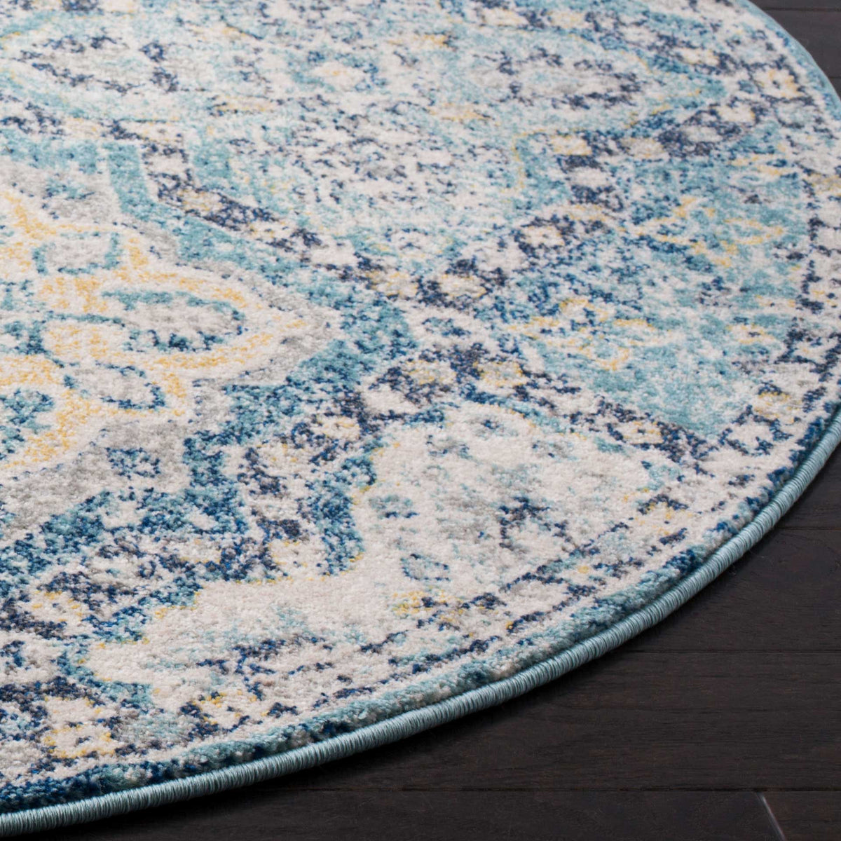 A neatly bound blue edge frames the rug's textured ivory and light blue pattern