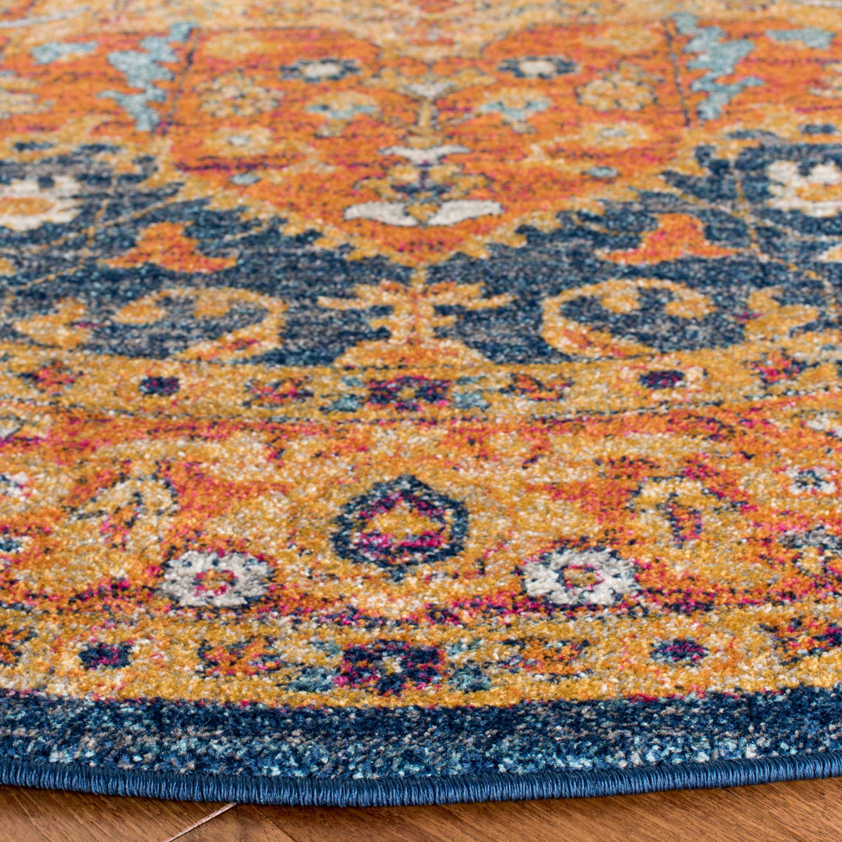 Speckled orange and blue pile reveals a floral border finished with a dark blue bound edge
