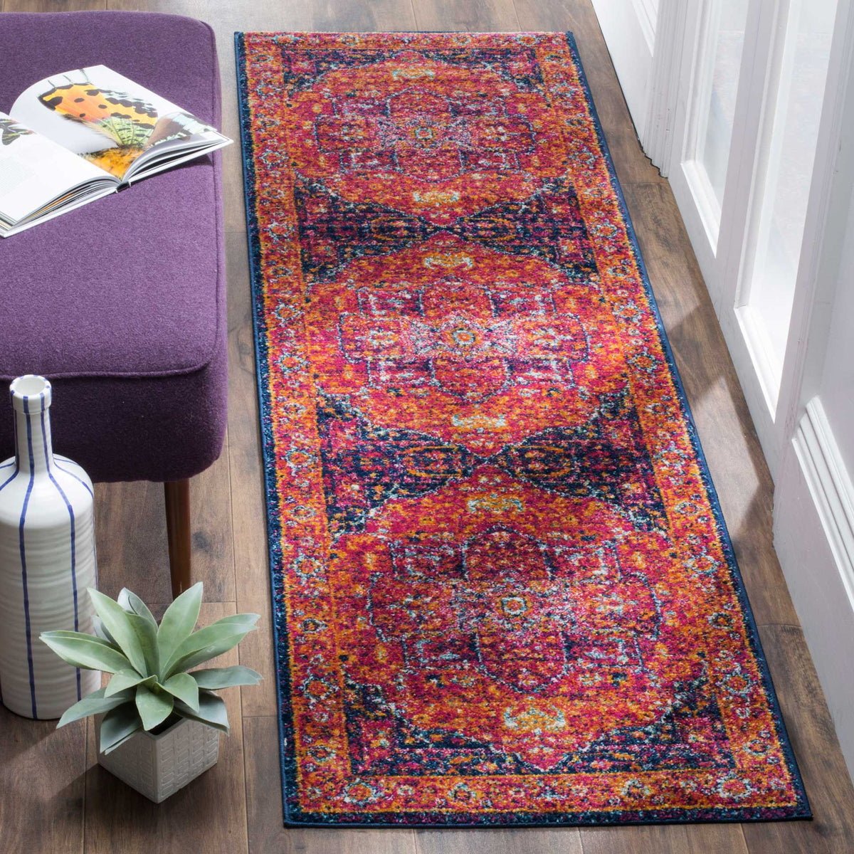 Fuchsia and orange runner livens a hallway with ornate medallions and a dark border