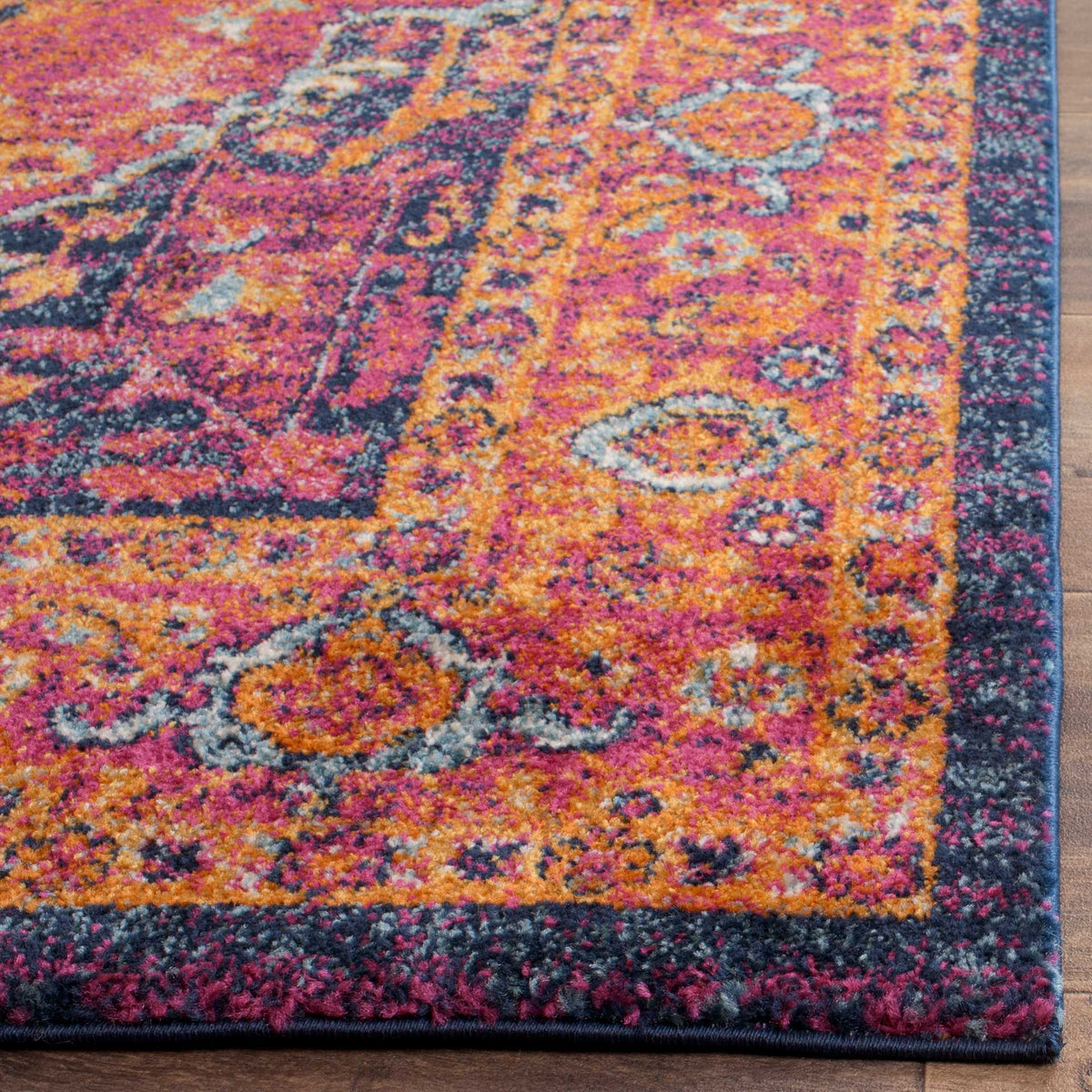 Saturated fuchsia and orange pile reveals finely detailed motifs and a dark finished edge.