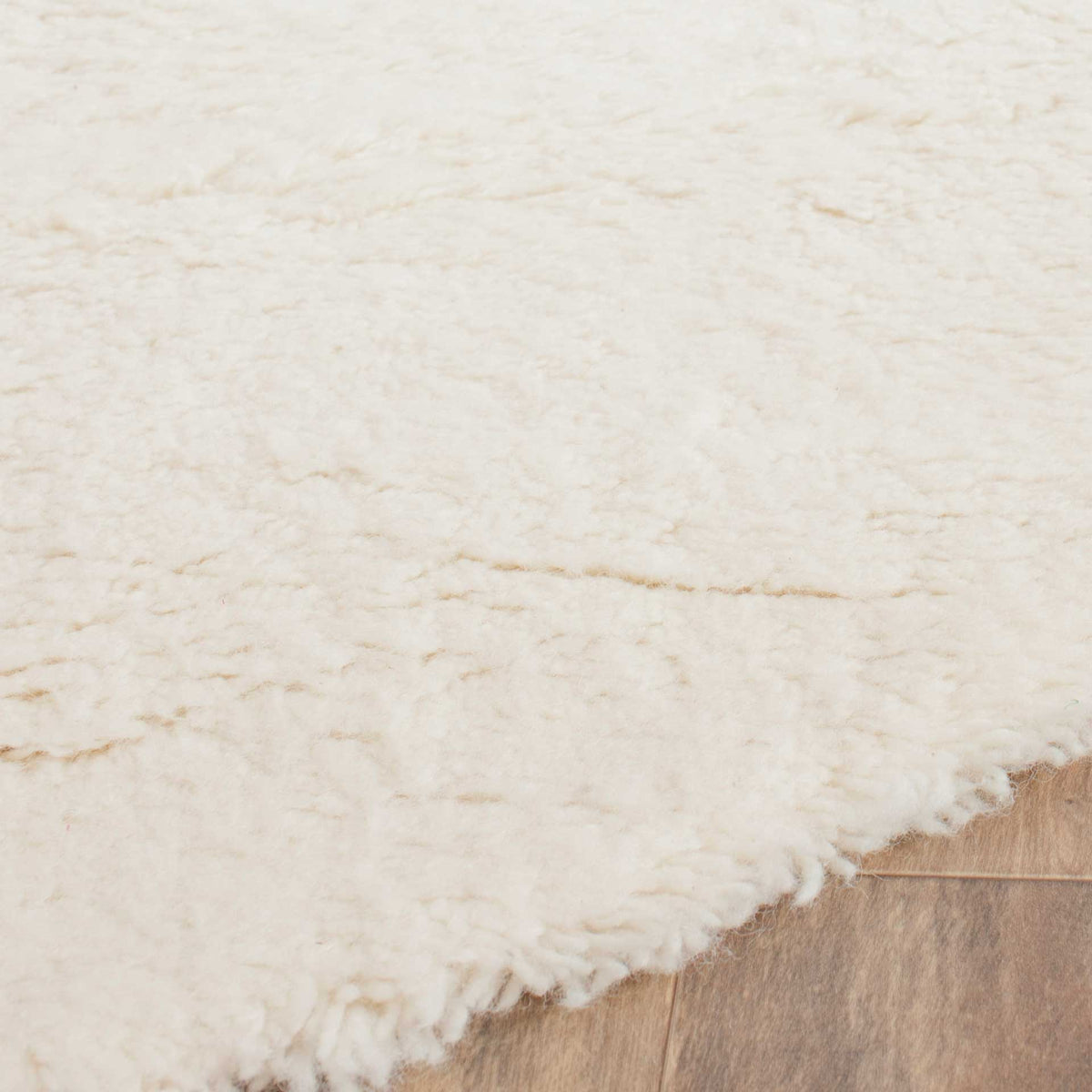Thick ivory wool pile and a soft, curved edge add inviting texture underfoot.