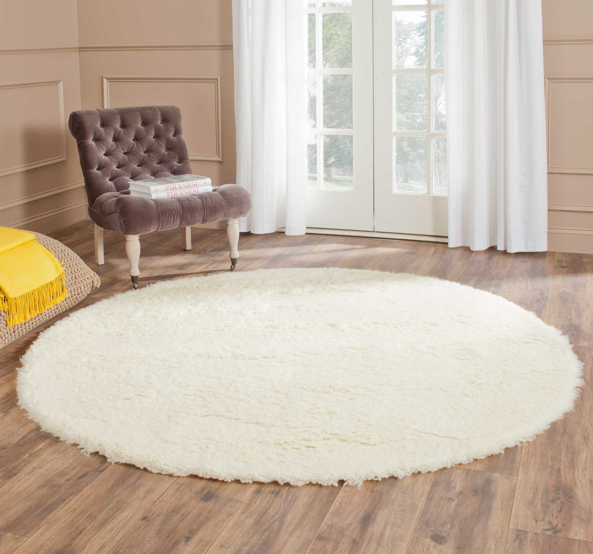 A round ivory shag rug adds cozy softness to a room with warm wood flooring.
