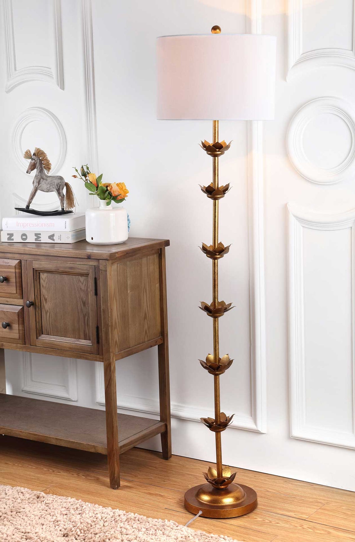 An off-white drum shade casts inviting light above the floor lamp's sculptural gold leaves.