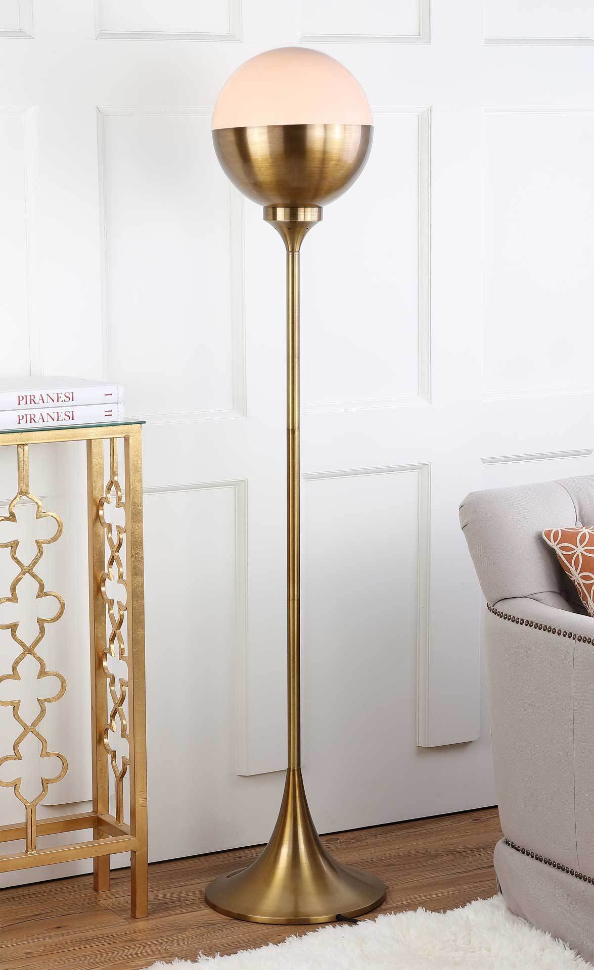 A softly glowing dome adds warmth to the brass-finish floor lamp beside a sofa.