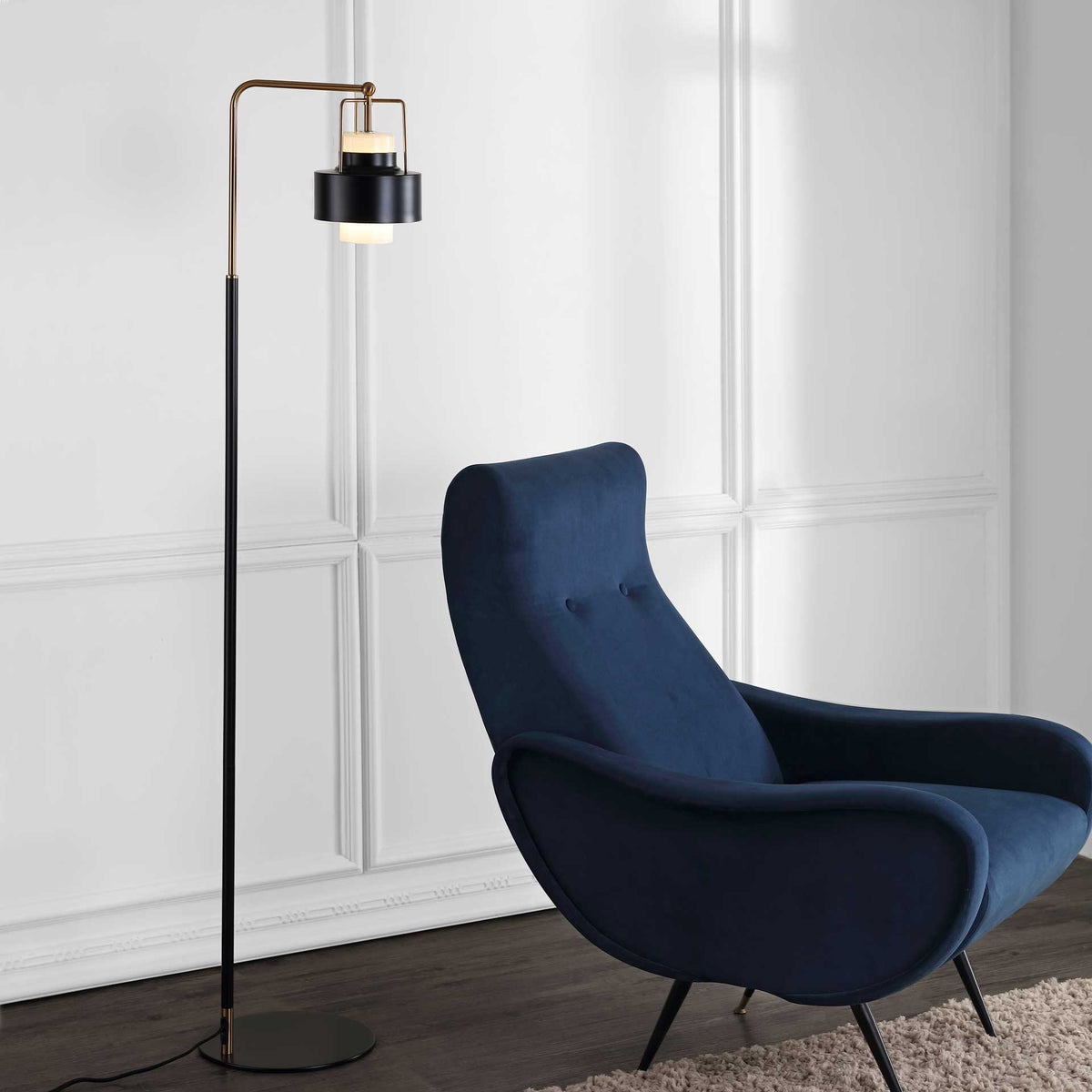 A brass-accented black floor lamp casts a warm glow beside a navy lounge chair.
