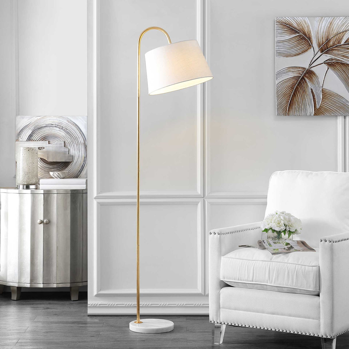 A glowing off-white shade tops a gold floor lamp with a marble base beside a white armchair