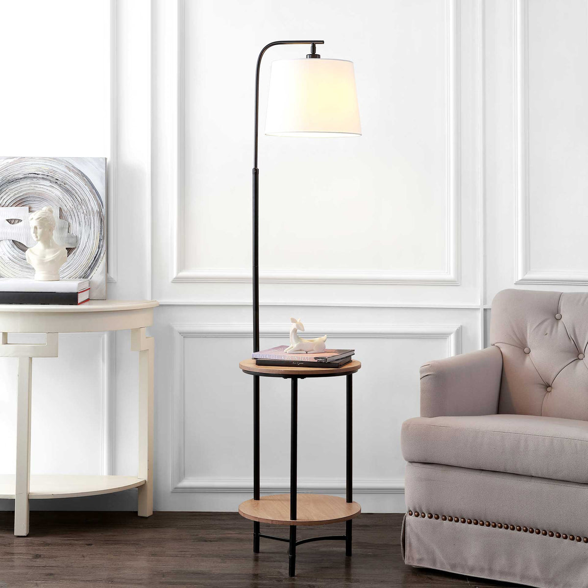 An arched black floor lamp brings warm light and two round shelves to a seating area