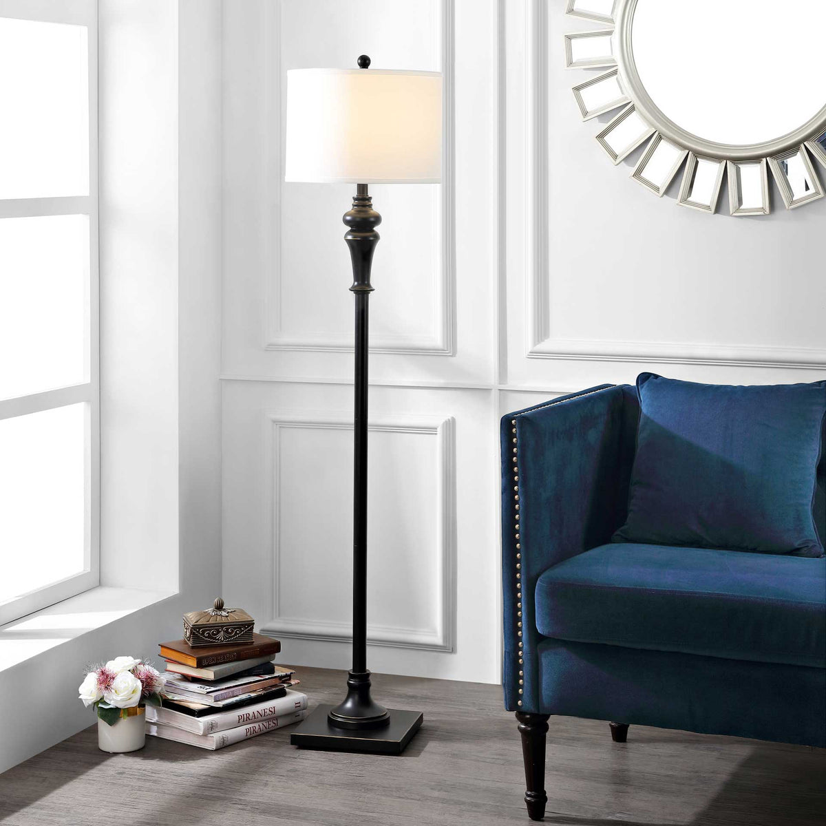 A glowing drum shade and sculpted black iron stem bring warm light beside a blue upholstered chair