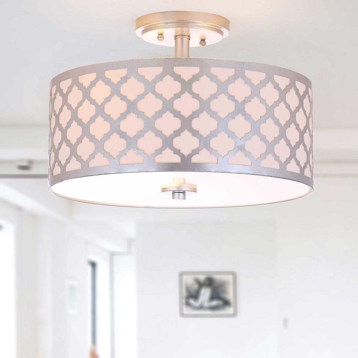 Warm light shines through the patterned shade, highlighting its silver quatrefoil frame
