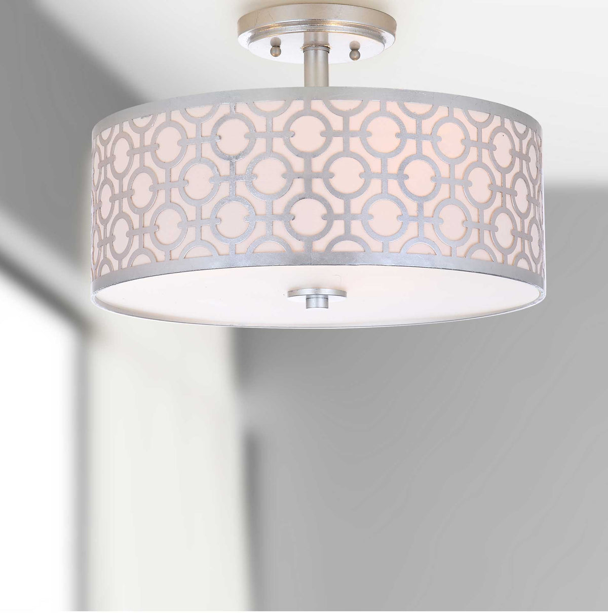 Soft illumination warms the patterned drum shade beneath a silver ceiling canopy