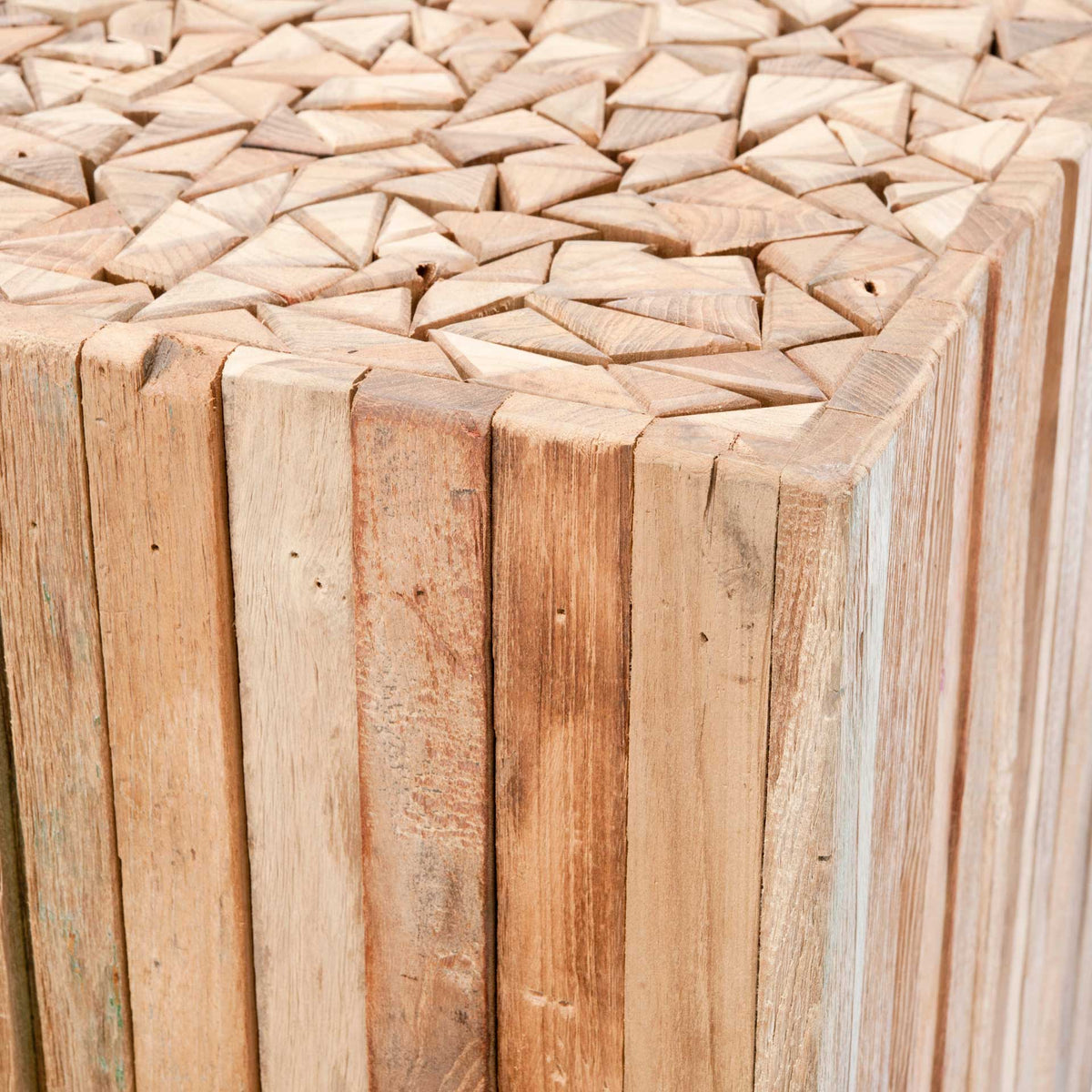An intricate mosaic of angled teak blocks tops the square table, framed by weathered vertical wood slats