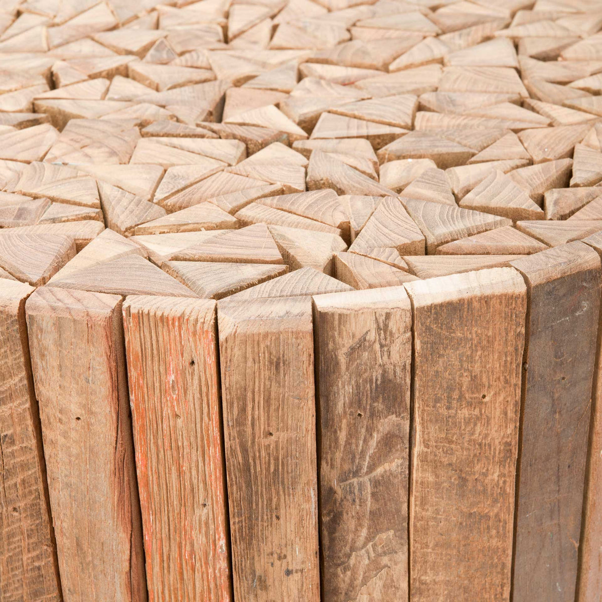 Angled teak blocks form a textured tabletop mosaic above straight wood slats in varied natural tones