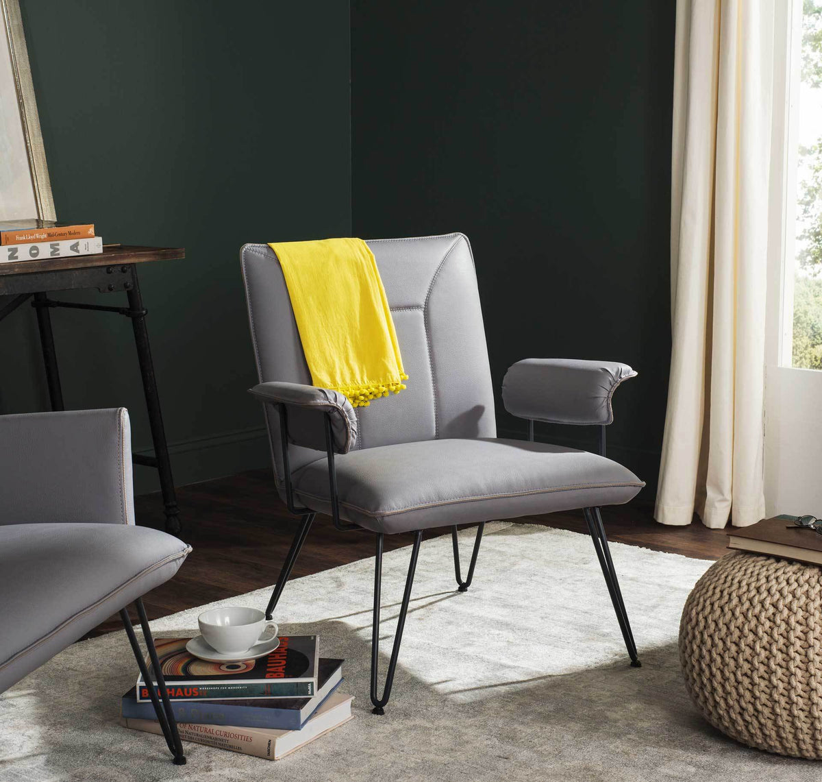 Gray upholstered armchair with cushioned arms and sleek hairpin legs adds relaxed retro style