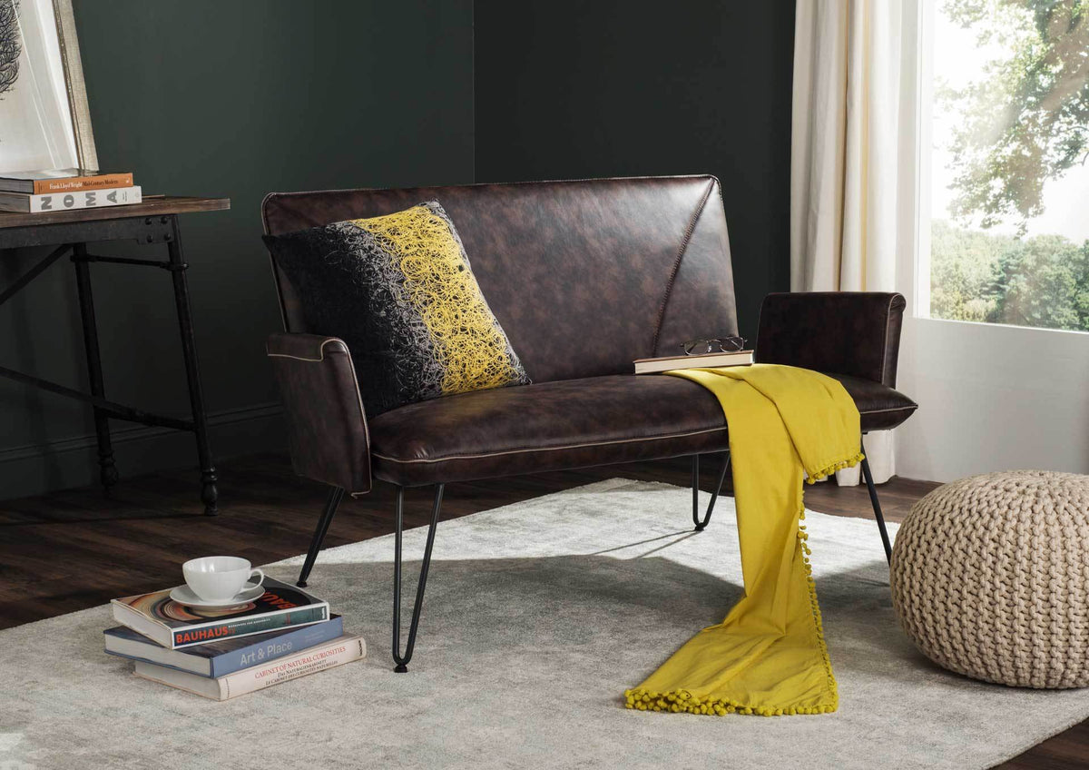 A brown faux leather settee brings vintage warmth to a living space with its sleek metal legs