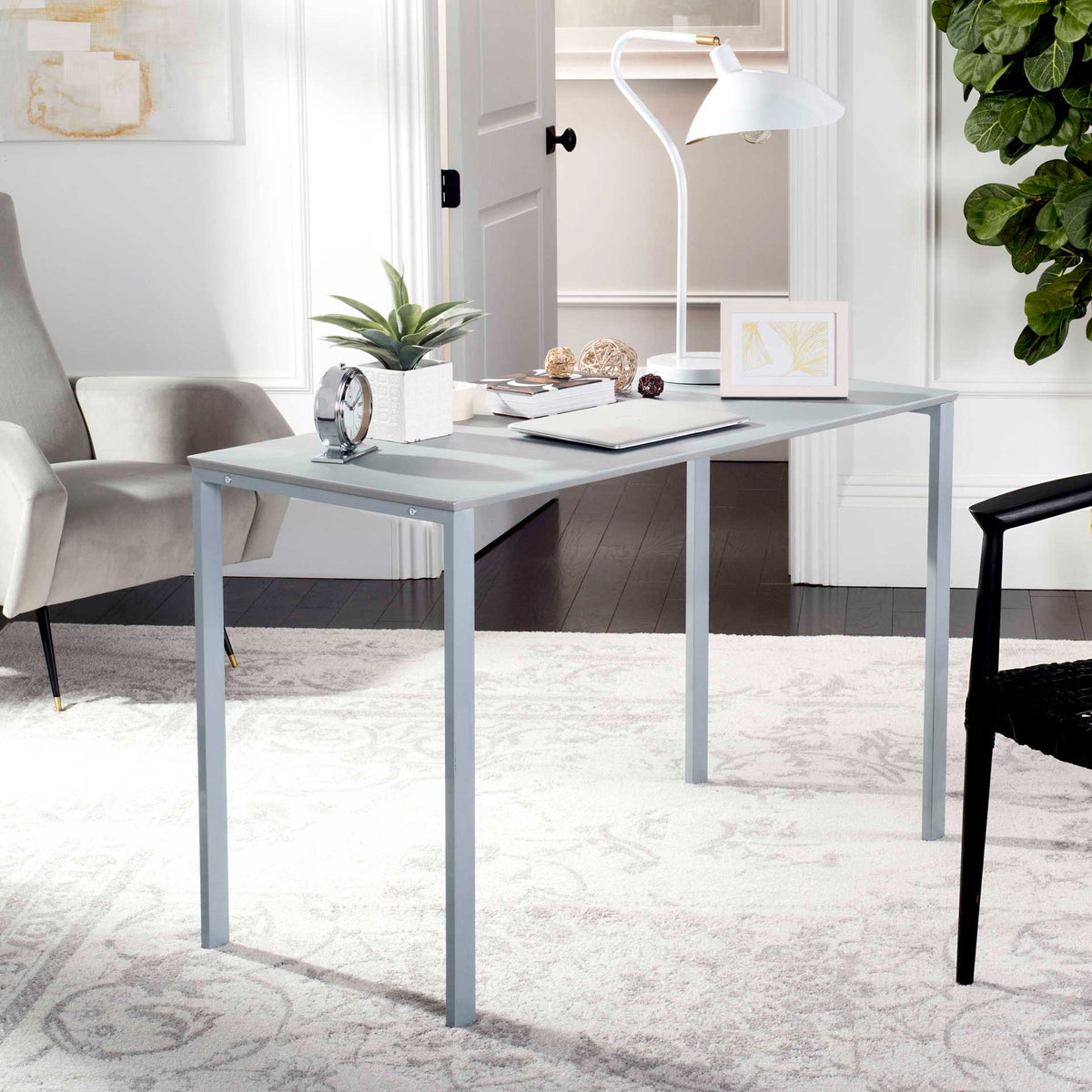 The light gray writing desk makes space for a laptop, lamp, and desktop essentials