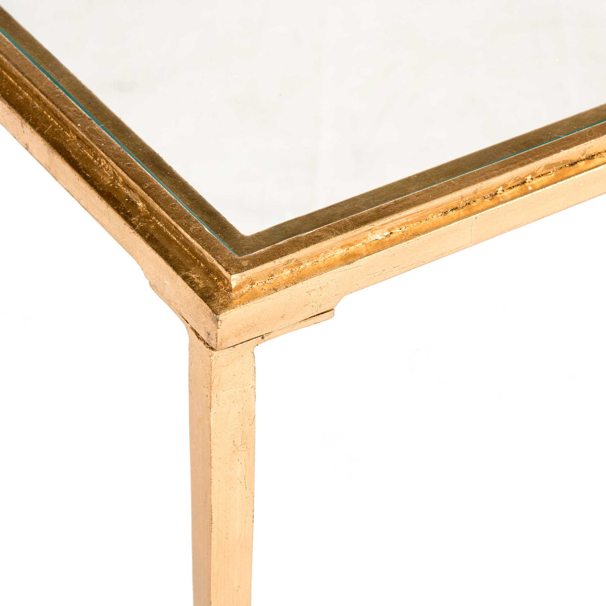 A clear glass tabletop sits within a textured antique gold frame