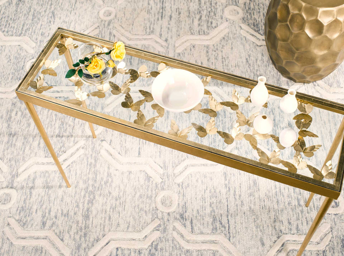 Gold butterflies shine through the clear glass top, leaving space to display vases and flowers.