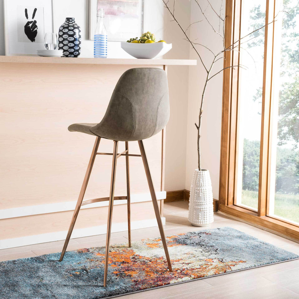 The curved taupe faux leather back shows neat seams above slim copper-toned supports.