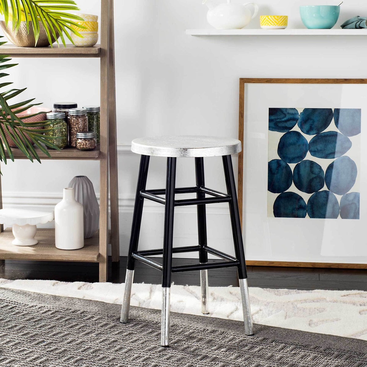 A compact black counter stool adds modern contrast with its silver seat and dipped silver feet.