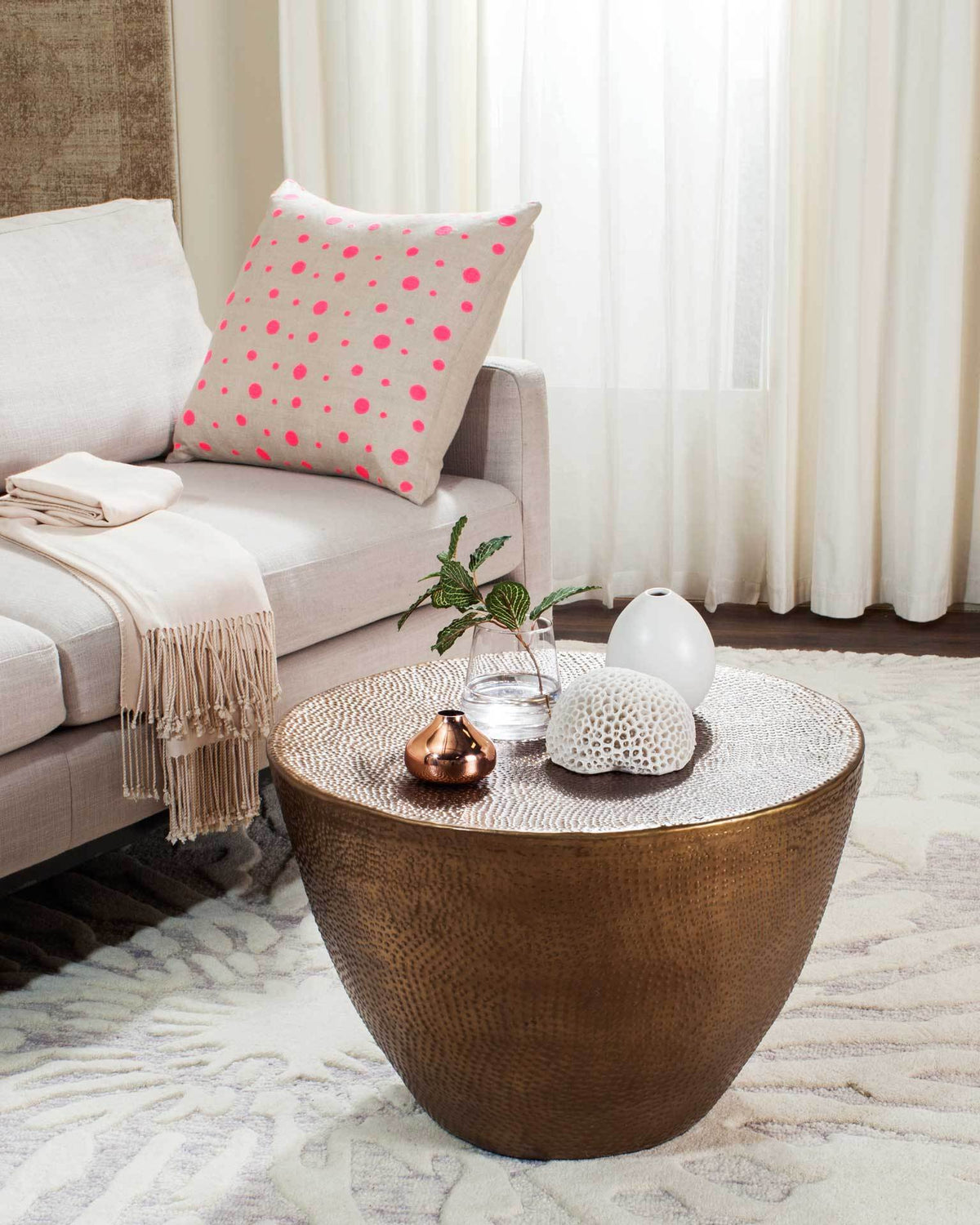 A brass-finished coffee table brings hammered texture and sculptural curves to a cozy living room.
