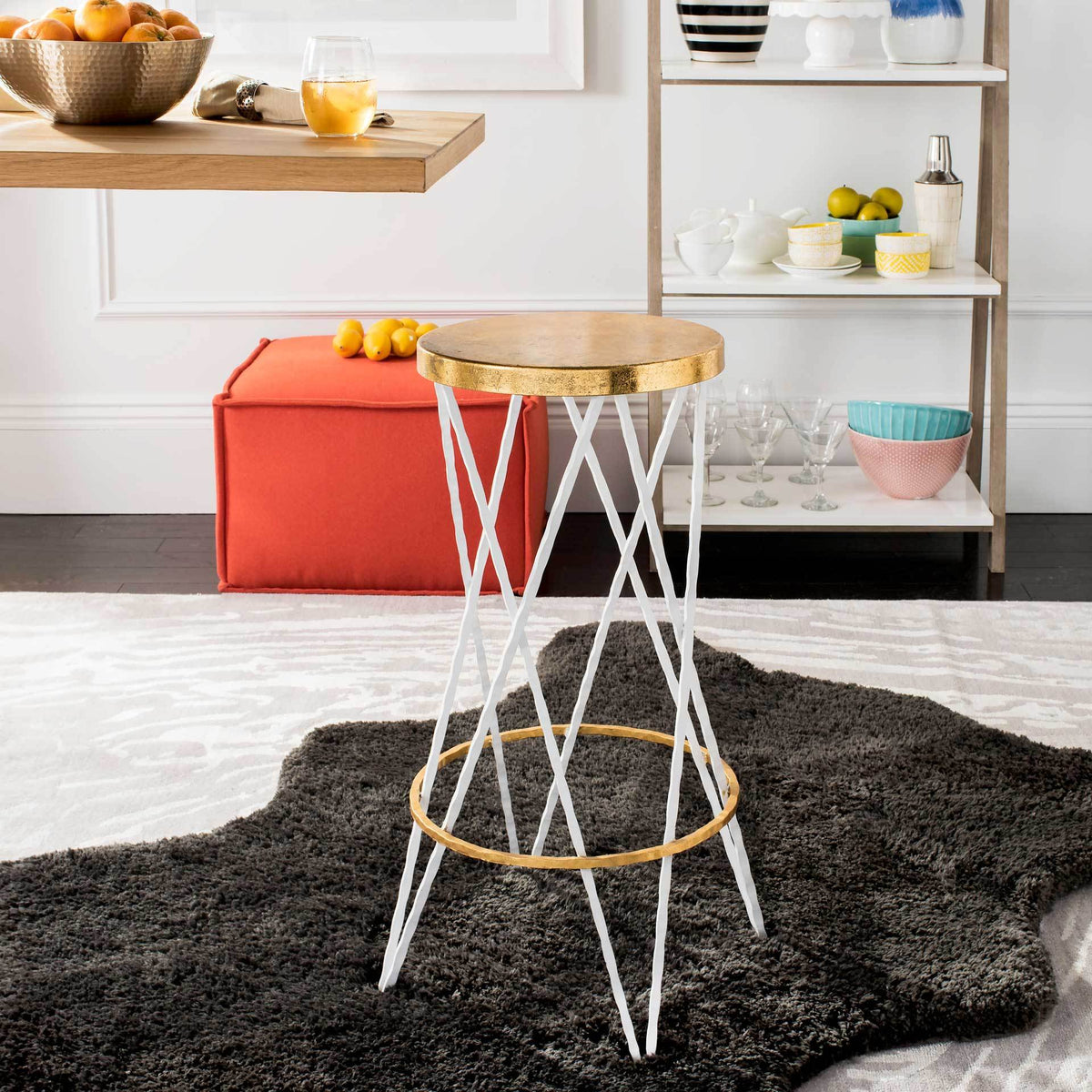 A round gold seat and crossed white legs bring a bright, sculptural accent to the room.