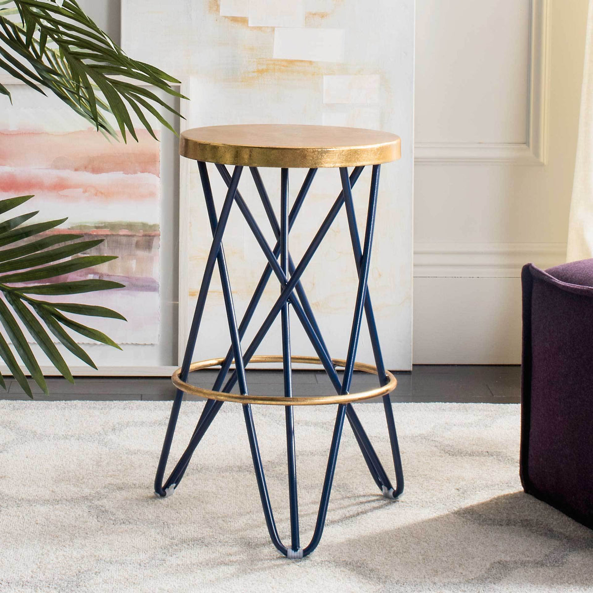 The counter-height stool pairs a round gold-leaf seat with crisscross navy legs and a gold footrest.