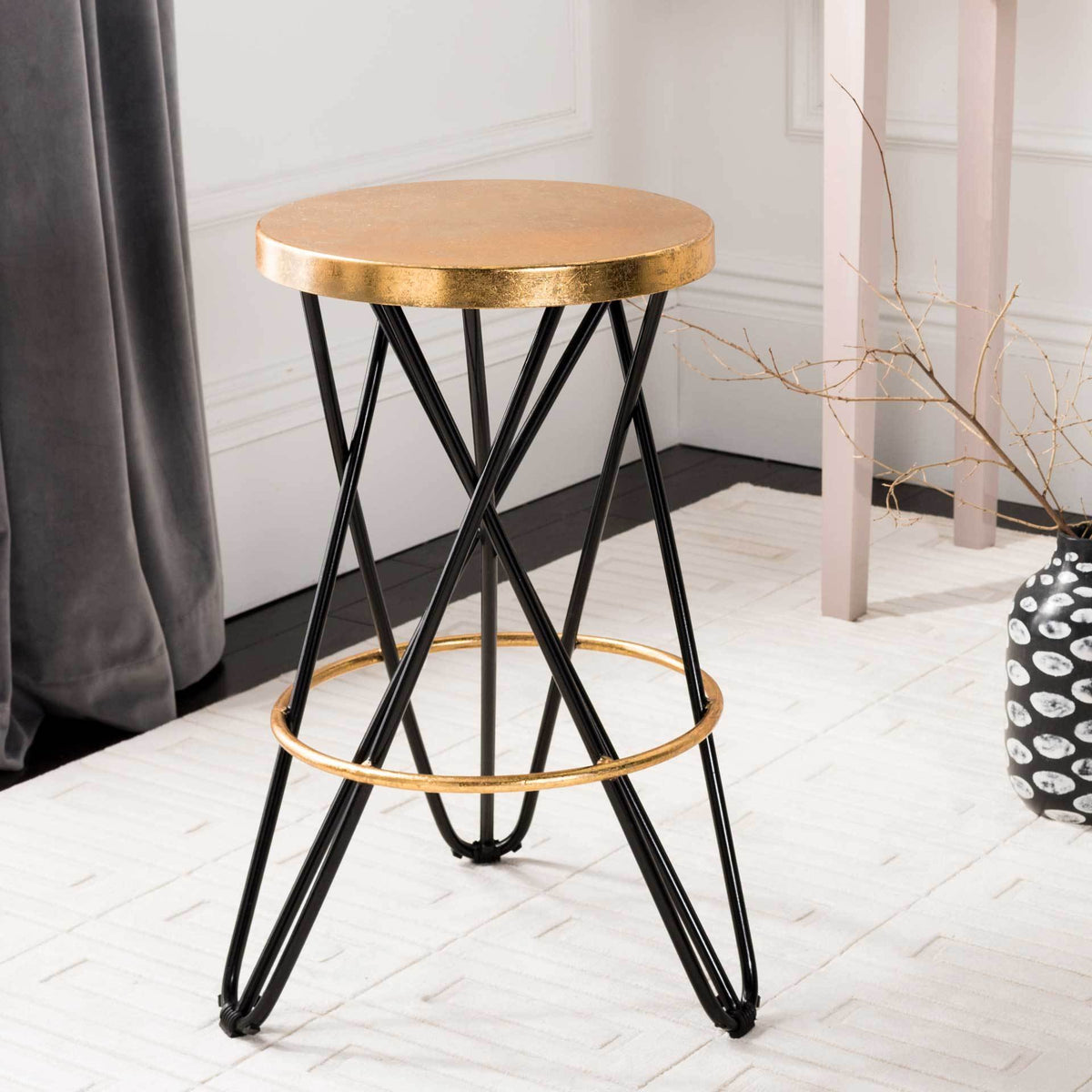 This backless counter stool combines a bold gold-leaf seat with crossed black iron legs.
