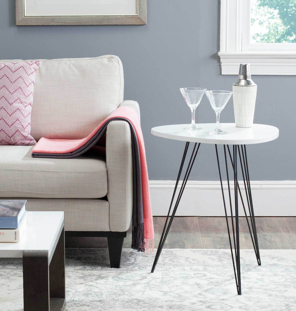 White round side table with airy black hairpin legs offers a perch for drinks beside a sofa