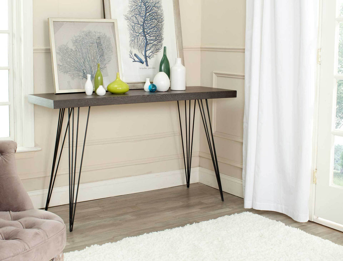Dark brown console table displays colorful vases and framed art above an open iron base.