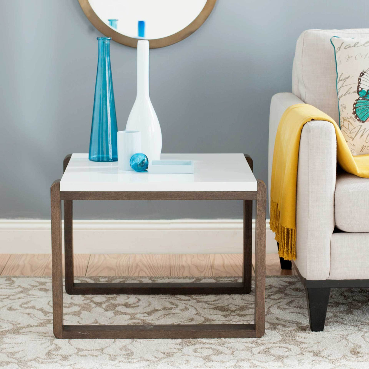 A white-topped end table with an airy dark brown frame adds a polished accent beside a sofa.