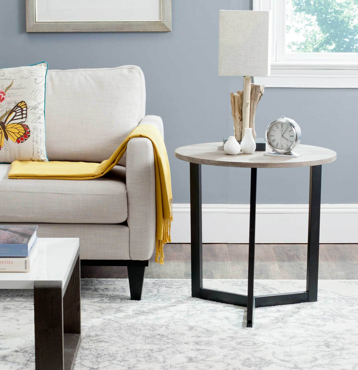 Warm oak-finished tabletop and slim black legs bring an airy accent beside a sofa.