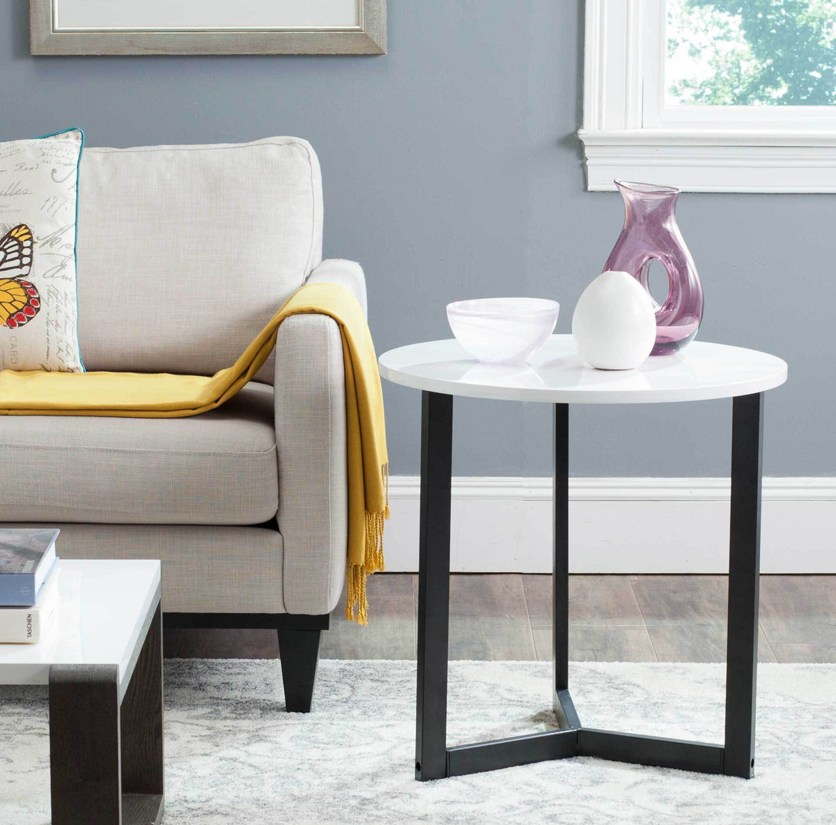 White round tabletop and open black base lend a crisp accent beside a sofa.